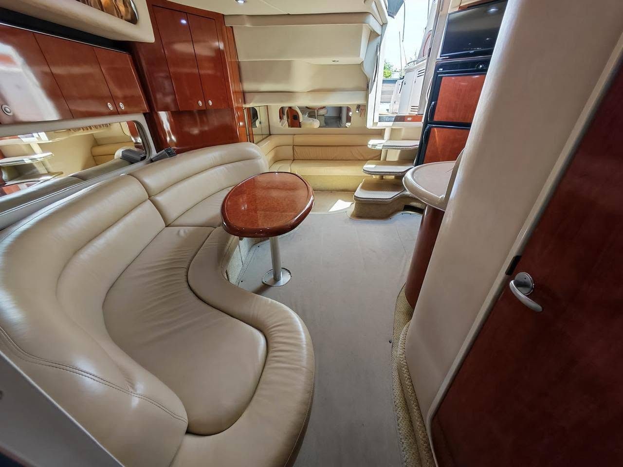 Salón interior del yate privado con sofás de piel y mesa de madera